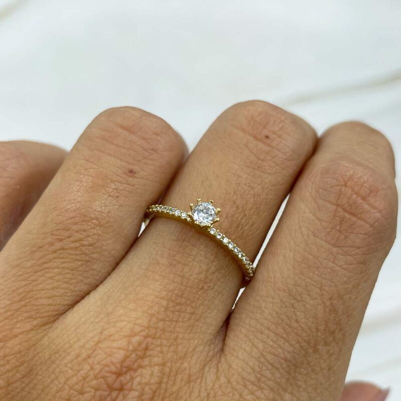 Detalle del anillo solitario en oro 18k con circones engastados y piedra central brillante.