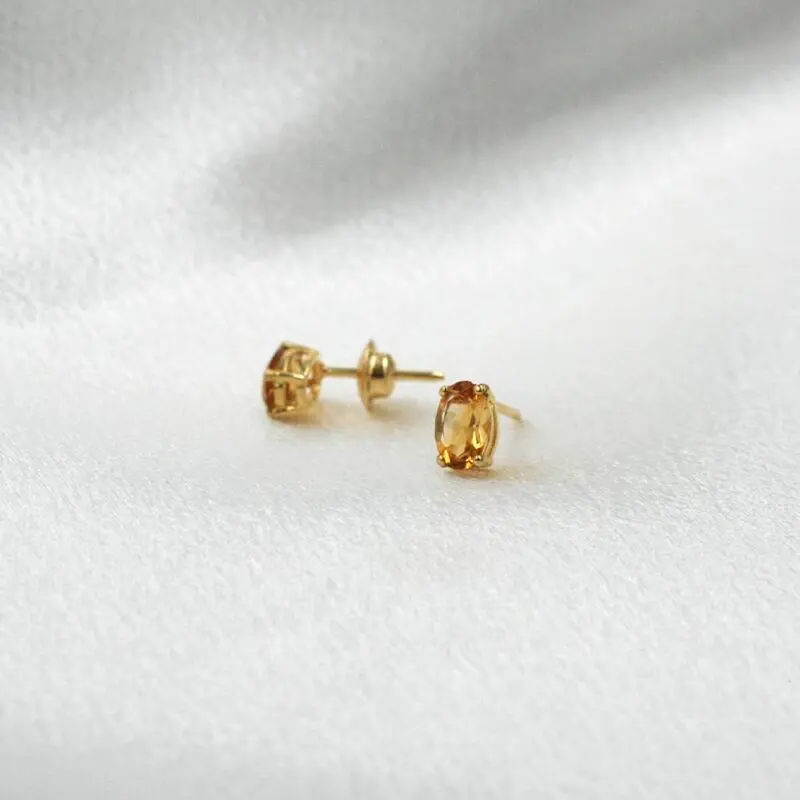 Aros minimalistas de oro 18k con citrino natural ovalado, diseño sutil.