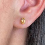 Aros de citrino en oro 18k colocados en la oreja, diseño fino y elegante.
