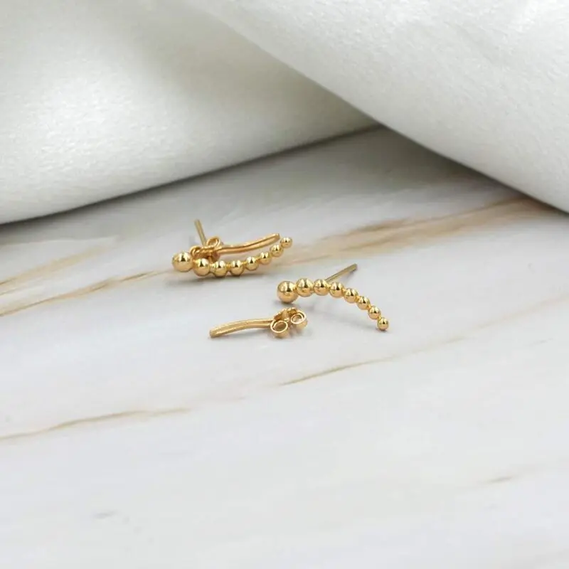 Earcuff minimalista de oro 18k con bolitas, ideal para combinar y usar a diario.