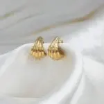 Aros Serena de oro 18k para mujer, diseño moderno de líneas curvas usado en la oreja.